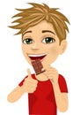 Cute boy eating chocolate showing thumbs up