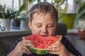 Cute boy eating watermelon at home. Real emotions without posing