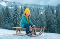 Cute boy enjoying a sleigh ride. Child sledding, riding a sledge play outdoors in snow on winter landscape. Outdoor Royalty Free Stock Photo