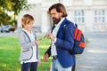 Cute boy and father walking to school. Bearded man with son wearing fashion suits outdoors. Father takes child to school