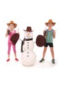 Cute boy and girl holding a cola bottle near a snowman with scarf and hat Royalty Free Stock Photo