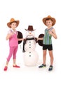 Cute boy and girl holding a cola bottle near a snowman with scarf and hat Royalty Free Stock Photo