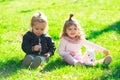 Cute boy and girl on summer field. Happy children playing sitting on green grass in spring park. Royalty Free Stock Photo