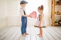 Cute boy gives a beautiful girl a gift. Little boy and girl in the room. Love concept. Royalty Free Stock Photo