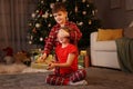 Cute little boy giving gift box to his sister near Christmas tree at home Royalty Free Stock Photo