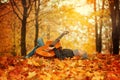 Cute boy with guitar, lying on the grass in autumn sunny day