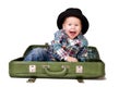 Cute boy in a hat sitting in a suitcase