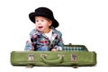 Cute boy in a hat sitting in a suitcase