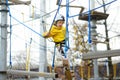 Cute boy having fun in Adventure Park for children amoung ropes, stairs, bridges. Frightened child overcomes his fear. Outdoor