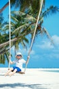 Cute boy having fun swinging at tropical island beach Royalty Free Stock Photo