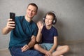 A cute boy with headphones is sitting on the floor with his dad and talking via video link Royalty Free Stock Photo