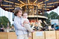 Cute boy and his baby sister standing in front of a carousel Royalty Free Stock Photo