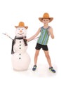 Cute boy holding a cola bottle near a snowman with scarf and hat Royalty Free Stock Photo