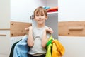 Cute boy holding hangers with clother in dressing room. Kid makes order in his wardrobe at home