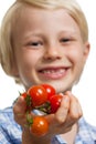 Cute boy holding out bunch of tomatoes