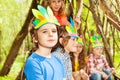 Cute boy in Injun`s headdress playing with friends Royalty Free Stock Photo