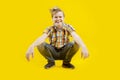 A cute boy laughing sits with a funny face and tousled hairstyle on a yellow background. Naughty teenager. Restless schoolboy Royalty Free Stock Photo