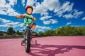 Cute boy on little bicycle in helmet ride at park over blue sky