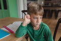 Cute boy looking away while sitting on dining table in a comfortable home Royalty Free Stock Photo