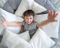 Cute boy is lying in a cocoon chair, surrounded by pillows on all sides Royalty Free Stock Photo