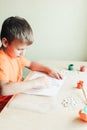 Cute boy making pumpkin from seeds on paper, Halloween DIY idea
