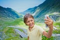 Cute boy making a selfie photo of Transfagarasan mountain road. Romania. Royalty Free Stock Photo