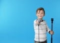 Cute boy with microphone on color background Royalty Free Stock Photo