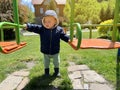 A cute boy of one and a half years standing near the swing. Backyard of the house. Children`s entertainment. Selective focus