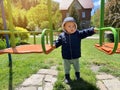 A cute boy of one and a half years standing near the swing. Backyard of the house. Childrens entertainment. Selective focus