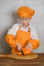 Cute boy in an orange suit chef`s cutting knife orange pepper