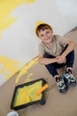 Cute boy with a paint roller. Happy kid helps parents to paint wall. New house for family