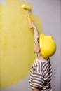 Cute boy with a paint roller. Happy kid helps parents to paint wall. New house for family