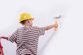 Cute boy with a paint roller. Happy kid helps parents to paint wall. New house for family