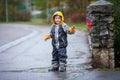 Cute boy in the park, playing in the rain, jumping in puddles