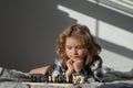 Cute boy are playing chess on bed at home. Kid thinking about chess. The concept of learning and growing children. Chess Royalty Free Stock Photo