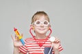 Cute boy playing doctor. Toy syringe, glasses and phonendoscope. Portrait Royalty Free Stock Photo