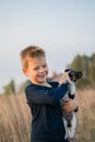 Cute boy playing with his dog in the meadow. Little puppy jack russel terrier on the walk with owner Royalty Free Stock Photo