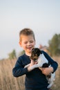 Cute boy playing with his dog in the meadow. Little puppy jack russel terrier on the walk with owner Royalty Free Stock Photo