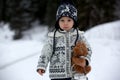 Cute boy playing with teddy bear in the snow, winter time. Little toddler playing with toys on snowy day Royalty Free Stock Photo