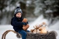 Cute boy playing with teddy bear in the snow, winter time. Little toddler playing with toys on snowy day Royalty Free Stock Photo
