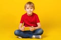 Cute boy playing video games on smartphone. Kid sitting on floor. Happy boy smiling. Child wears red tshirt