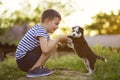 A cute boy plays with husky puppy outdoor. A child holds the puppys paws in his hands