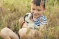 A cute boy plays with husky puppy sitting in grass on a meadow. Puppy in the hands of a child Royalty Free Stock Photo