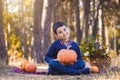 Cute boy with a pumpkin in his hands in a pine forest