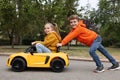 Cute boy pushing children`s car with little girl outdoors