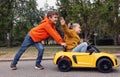 Cute boy pushing children`s car with little girl outdoors