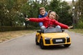 Cute boy pushing children`s car with little girl outdoors. Space for text