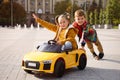 Cute boy pushing children`s car with little girl outdoors on sunny day