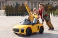 Cute boy pushing children`s car with little girl outdoors on sunny day