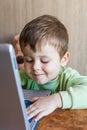 Cute boy is pushing laptops keyboard and he is looking at the screen. Royalty Free Stock Photo